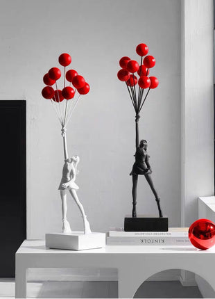 Elegant statuettes of a girl holding red balloons - minimalistic decor accents.