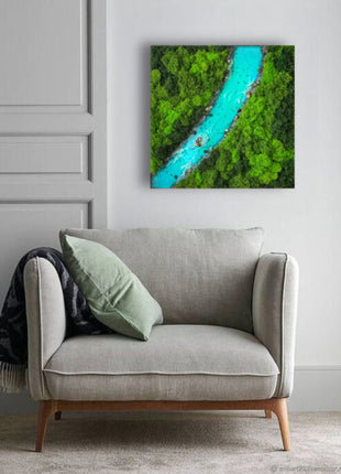 Gray sofa with a green pillow against a wall with a nature-themed painting.