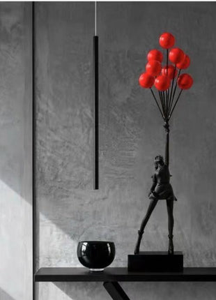 Black statuette of a girl holding red balloons - minimalistic decor accents.