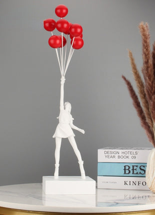 White statuette of a girl holding red balloons - minimalistic decor accents.