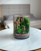 Glass candle with a miniature landscape design on a marble surface.
