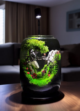 Decorative terrarium with plants and small figures on a table in a room.
