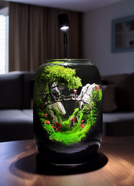 Decorative terrarium with plants and small figures on a table in a room.